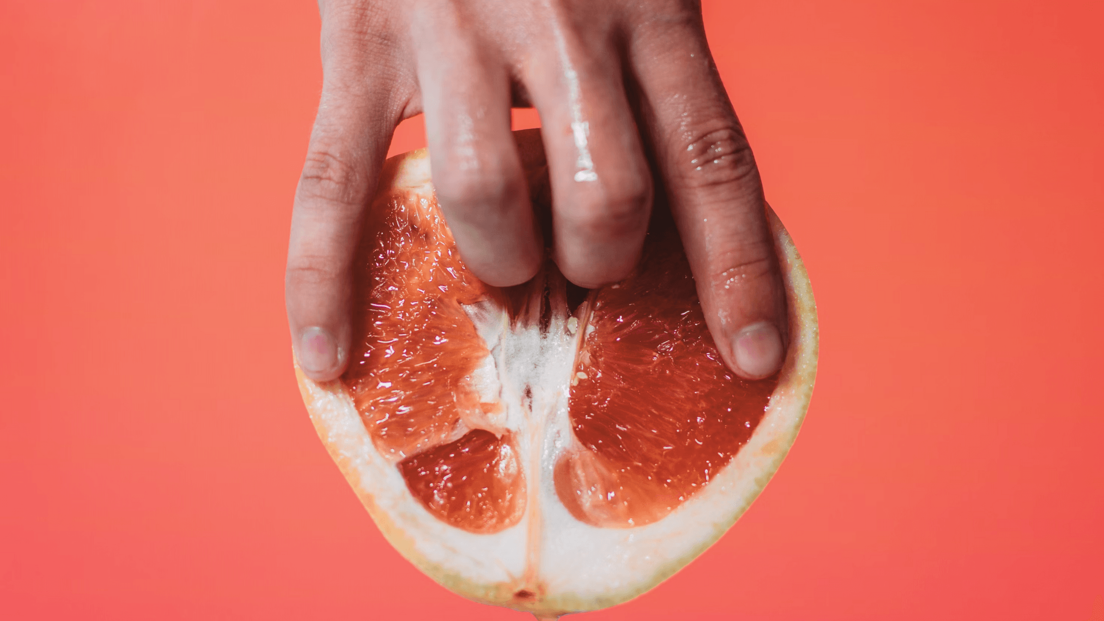 Fingers entering grapefruit symbolizing lesbian sex and pleasure