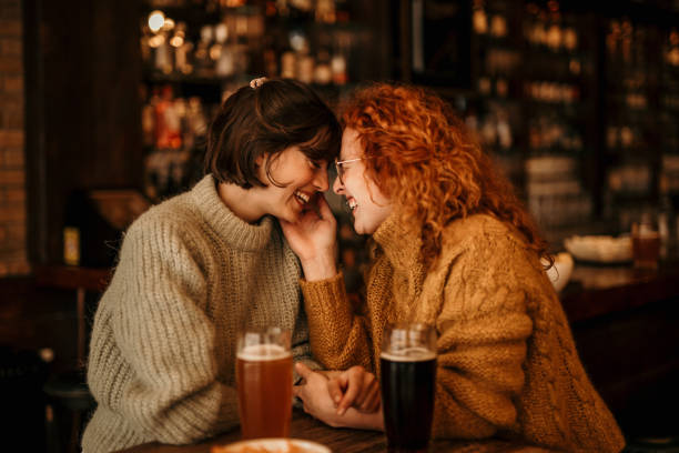 Queer couple sharing a tender moment on a cozy date at a bar
